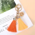 Macro detail of vibrant orange and yellow silk tassel keychain with decorative gold bell - Yellow+Orange