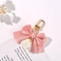 Close-up of a sweet pink ribbon bow keychain featuring a delicate white pearl cube. - Pink