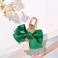 Close-up of green satin ribbon bow keychain with white pearl cube charm - Green