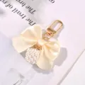 Elegant cream satin bow keychain with a pearl cube charm and gold metal clasp - White