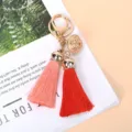 Close-up of gold filigree bell and dual-colored tassels on a keychain pendant - Red and Pink