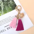 Détail macro d'un charme cloche doré et de glands rose et violet vibrants sur un porte-clés - Rose Et Fuchsia