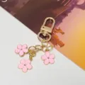 Encantador llavero adornado con tres flores de esmalte rosa y acabado dorado - Rosa Cierre G Con Cadena