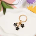 Détail rapproché d'un porte-clés doré avec trois élégantes fleurs en émail noir pendentifs - Noir