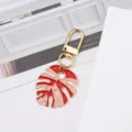 Elegant metal monstera leaf keychain charm featuring red and pink enamel on a gold base - Pink + Bright Red