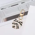 Stylish golden metal monstera leaf keychain featuring black and white enamel finish for bags - White + Black