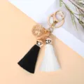 Elegant gold bell keychain with premium black and white tassels for car keys or handbag charms - Black + White