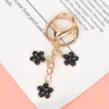 Charming gold metal keychain featuring three black enamel cherry blossom flower charms - Lobster Clasp Style / Black