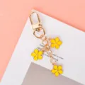 Yellow triple flower charm keychain with gold-tone lobster clasp on pink background - Yellow G-clasp With Chain