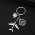 Zilveren metalen reis-sleutelhanger met vliegtuig-, globe- en kompas-bedeltjes op zwart - Vliegtuig Kompas Wereldbol