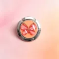 Nahaufnahme eines faltbaren Metall-Handtaschenhalters mit einem funkelnden Schmetterlingsdekor. - Stil 1 (Orange + Roter Schmetterling)