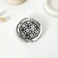 Detailed view of portable foldable metal bag hook with black and white checkerboard flower pattern - Small Floral Pattern / Silver