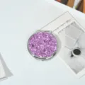 Detail view of a compact pink glitter makeup mirror with a polished metal frame - Sparkle Purple