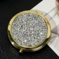 Detailed view of the sparkling rhinestone surface on a gold circular folding mirror - 70mm / Twinkling silver diamond (gold frame)