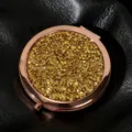 Close-up of a golden glitter round folding makeup mirror with studs on black leather. - 70mm / Champagne gold diamond (rose gold)