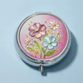 Portable circular metal pill box with embossed floral design on pink background - Pink & Blue Contrast Flowers (Round Silver Frame)