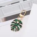 Elegant green and gold monstera leaf enamel keychain for bags and accessories - Green + Black