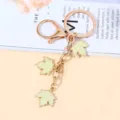 Gold metal keychain with three pale green enamel maple leaf charms as a bag accessory. - Light Yellow Style