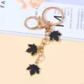 Elegant gold-tone metal keychain featuring three black enamel maple leaf charms for bags - Black Style