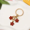 Golden keychain featuring three elegant red enamel flower charms for bag decoration - Dark Red