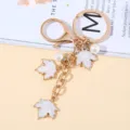 Elegant golden metal keychain charm with white enamel maple leaf pendants and pearls - White Pearl Style