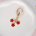 Elegant gold metal keychain featuring three vibrant red enamel flower charms for bags - Red With Lobster Clasp