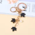 Elegant gold-tone maple leaf metal keychain featuring black enamel charms and white pearls - Black Pearl Style