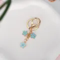 Gold-plated metal keychain featuring three light blue enamel flower charms for bags - Blue With Lobster Clasp