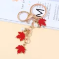 Red maple leaf keychain featuring white pearls and elegant gold-toned metal chain. - Red Pearl Style