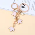Elegant golden maple leaf keychain with pink enamel charms and white pearl accents - Pink Pearl Style