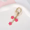 Elegant gold metal keychain featuring three vibrant pink enamel flower charms for bags - Peach Pink With Lobster Clasp