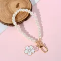 Detailed view of pearl phone strap with white and pink enamel flower charms and gold clasp - White & Pink Enamel Flower Style (Style 14)