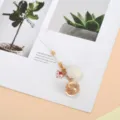 Detailed shot of cute fox phone strap with gold filigree bell and white pom-pom charm - Pom-pom Hollow Ball Fox 1
