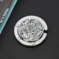 Primer plano detallado de un gancho plegable para bolsos con adornos de strass brillantes. - Estilo con Brillantes / Circón Blanco
