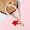 Detail of pearl phone strap featuring a red flower charm and golden lobster clasp. - Red Gold-Trim Flower Style (Style 17)