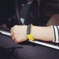 Detail view of a stylish yellow LED sports bracelet worn on a wrist in a car setting - Yellow