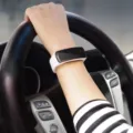 Primer plano de una elegante pulsera deportiva digital con LED blanco usada al conducir - Blanco