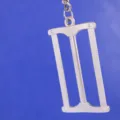 Primer plano de un creativo llavero metálico en forma de sierra sobre fondo azul sólido - Estilo Sierra para Metales (13)