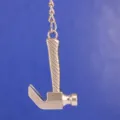 Primer plano detallado de un llavero miniatura de martillo de orejas hecho de metal plateado. - Estilo Martillo de Orejas (8)