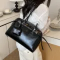 Elegant black glossy faux leather shoulder bag with silver buckle details and small pouch. - Black
