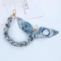 Detailed macro shot of the elegant woven blue scarf and gold chain phone strap accessory - Style O