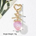 Detail view of sweet pink strawberry keychain with rhinestone bow and heart clasp - Transparent Purple