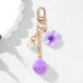 Close-up of a purple resin flower and fluffy pom-pom keychain charm for bag decor - Purple