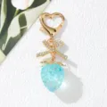 Close-up of cute blue resin strawberry keychain with heart clasp and sparkling bow charm. - Transparent Blue