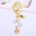 Detailed view of the white ceramic rabbit pendant with gold bell and ring - Rabbit