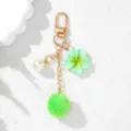 Detailed view of a mint green resin flower and pom-pom keychain with a white pearl charm. - Green