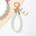 Detailed view of pearl letter L charm on a heart-shaped golden keychain - Letter E Style / Pearl White