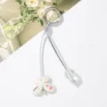 Primer plano de un lindo colgante de flor blanca y una cuenta en un llavero de cordón plata. - Perla de Mariposa