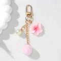 Detail view of pink resin flower, pearl, and soft pom-pom keychain with gold clasp - Pink