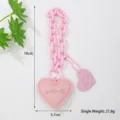 Vista detallada del llavero de corazón de cuero rosa con cadena y medidas precisas - Rosa
